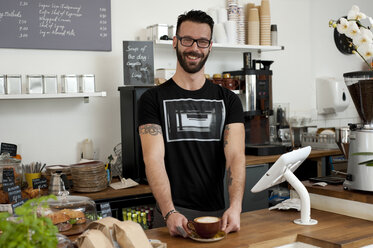 Porträt eines Café-Kellners, der Kaffee vom Tresen serviert - CUF28079
