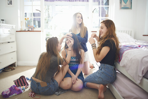 Vier Teenager-Mädchen machen sich im Schlafzimmer fertig, lizenzfreies Stockfoto