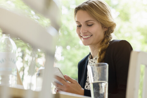 Junge Frau im Café liest Texte auf dem Smartphone, lizenzfreies Stockfoto