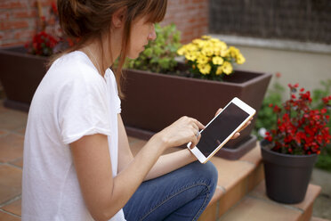 Side view of mid adult woman sitting outdoors using digital tablet - CUF28208