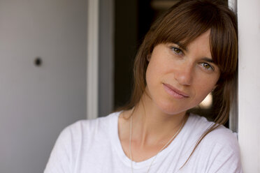 Portrait of mid adult woman leaning against doorframe, looking at camera - CUF28209