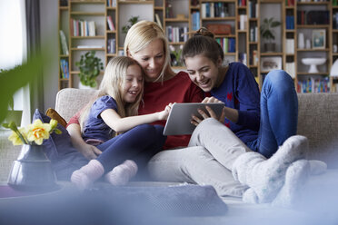 Mutter und ihre Töchter sitzen auf der Couch und haben Spaß mit einem digitalen Laptop - RBF06242