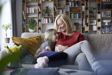 Mother and daughter cuddling on couch - RBF06247