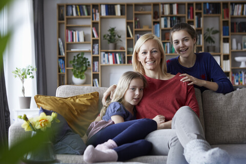 Mutter und ihre Töchter kuscheln und haben Spaß, sitzen auf der Couch, lizenzfreies Stockfoto