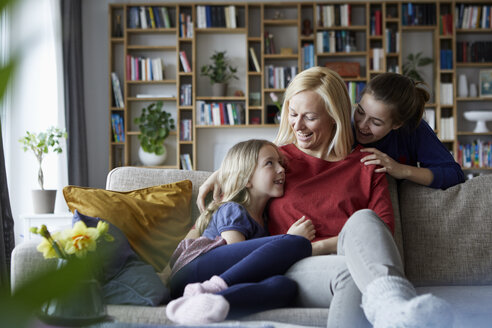 Mother and her daughters cuddling and having fun, sitting on couch - RBF06249