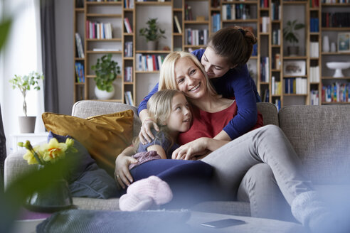 Mother and her daughters cuddling and having fun, sitting on couch - RBF06250