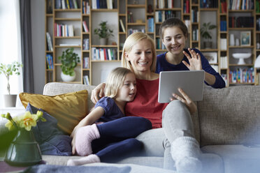 Mother and her daughters sitting on couch, having fun using digital laptop - RBF06252