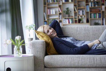 Frau entspannt sich zu Hause, liegt auf der Couch - RBF06264