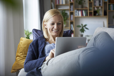 Frau mit digitalem Tablet, entspannt auf der Couch - RBF06266