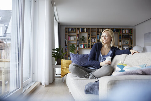 Frau entspannt sich zu Hause, sitzt auf der Couch - RBF06269