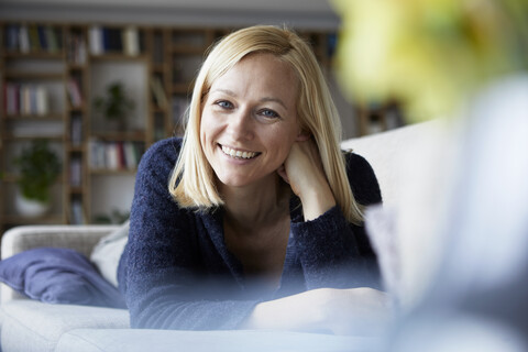 Frau entspannt sich zu Hause, sitzt auf der Couch, lizenzfreies Stockfoto