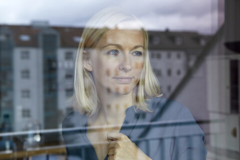 Blonde Frau schaut aus dem Fenster, lizenzfreies Stockfoto