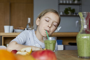 Mädchen sitzt in der Küche und trinkt selbstgemachten Fruchtsmoothie - RBF06280