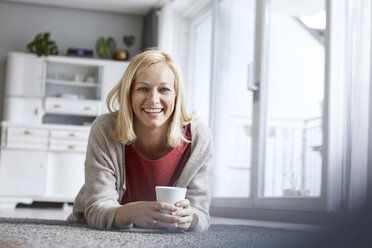 Glückliche Frau, die sich zu Hause entspannt und Kaffee trinkt - RBF06286