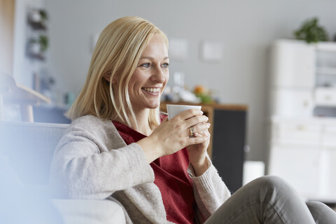 Glückliche Frau, die sich zu Hause entspannt und Kaffee trinkt, lizenzfreies Stockfoto