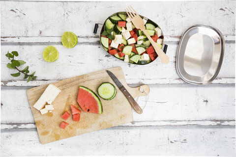 Lunchbox, Zubereitung von Wassermelonensalat mit Feta, Gurke, Ment und Limettendressing, lizenzfreies Stockfoto