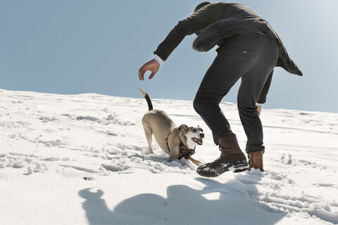 Mann spielt mit Hund im Winter, hat Spaß im Schnee, lizenzfreies Stockfoto