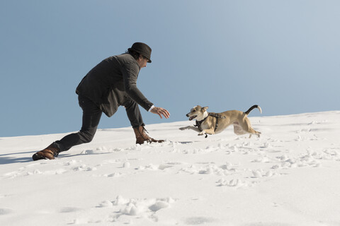 Man playing with dog in winter, having fun in the snow stock photo