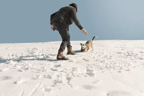Mann spielt mit Hund im Winter, hat Spaß im Schnee - REAF00272