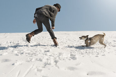 Mann spielt mit Hund im Winter, wirft Schnee - REAF00275