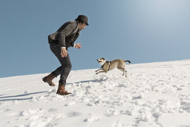 Mann spielt mit Hund im Winter, wirft Schnee - REAF00276