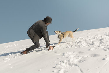 Mann spielt mit Hund im Winter, wirft Schnee - REAF00277