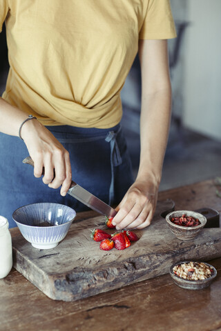 Frau bereitet das Schneiden von Erdbeeren auf einem Schneidebrett vor, lizenzfreies Stockfoto