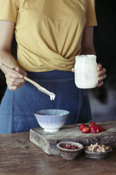 Frau bereitet Müsli, Joghurt, frische Erdbeeren und Müsli zu - ALBF00345
