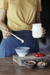 Woman preparing muesli, yoghurt, fresh strawberries and granola - ALBF00345