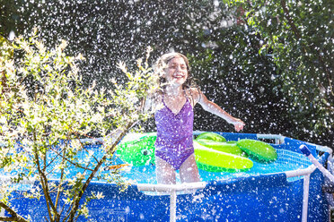 Lachendes Mädchen im Planschbecken, das mit Wasser spritzt - SARF03776