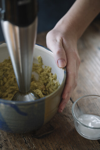 Frau bereitet Teig für hausgemachte vegane Kichererbsenplätzchen vor, Nahaufnahme, lizenzfreies Stockfoto