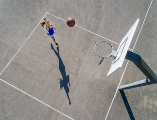 Aerial view of young woman playing basketball - STSF01605