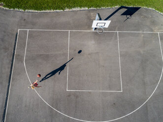 Aerial view of young woman playing basketball - STSF01606