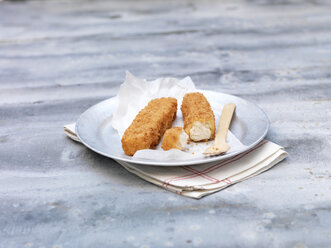 Plate of fried chunky breaded fish fingers on steel table - CUF28294