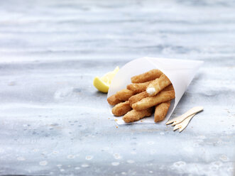 Greaseproof paper cone with lemon sole goujons on steel table - CUF28295