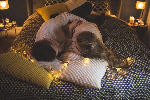 Romantic young couple cuddling in bed with fairy lights - AWF00047