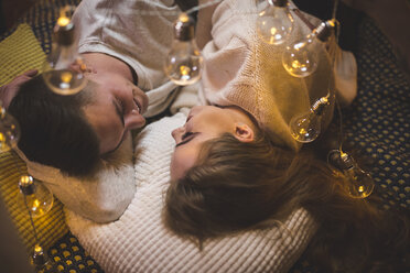 Romantisches junges Paar kuschelt im Bett mit Lichterketten - AWF00049