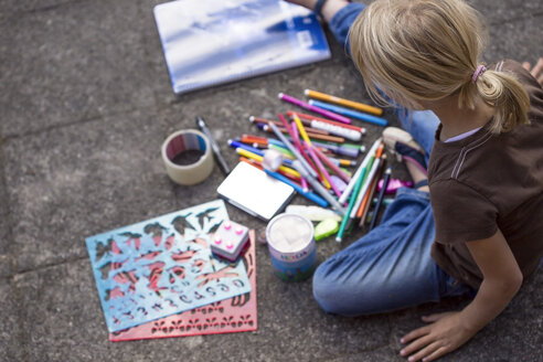 Girl sitting on pavement with many drawing materials - JFEF00871