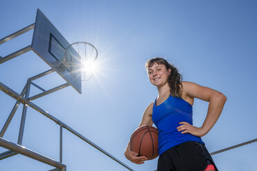 Junge Frau mit Basketball gegen die Sonne - STSF01611