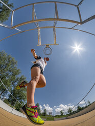 Young woman playing basketball against the sun - STSF01614