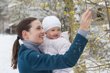 Portrait of happy mother with baby girl in snow-covered landscape - DIGF04572