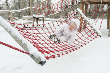 Baby girl having fun on swing in winter - DIGF04582