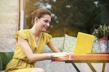 Junge Frau mit Laptop vor einem Café - CUF28508