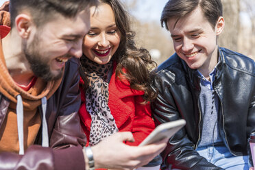 Russland, Moskau, Gruppe von Freunden im Park, die zusammen Spaß haben und Smartphones benutzen - WPEF00403