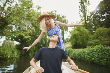 Young woman with boyfriend standing in rowing boat on river - CUF28605