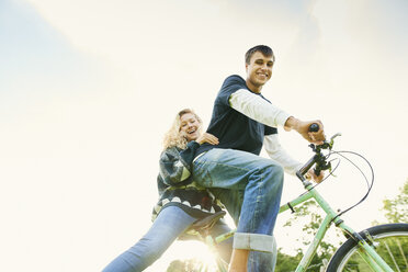 Low angle portrait of young couple on bicycle - CUF28612