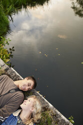 Overhead view of young couple lying on river footbridge - CUF28622