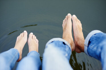 Overhead view of bare feet and legs of young couple on river footbridge - CUF28624