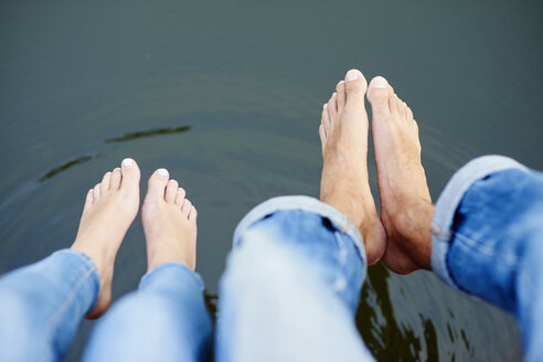 Draufsicht auf nackte Füße und Beine eines jungen Paares auf einem Flusssteg - CUF28624