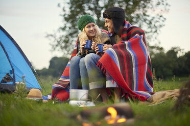 Junges Campingpärchen sitzt mit einer Tasse Tee am Lagerfeuer - CUF28629